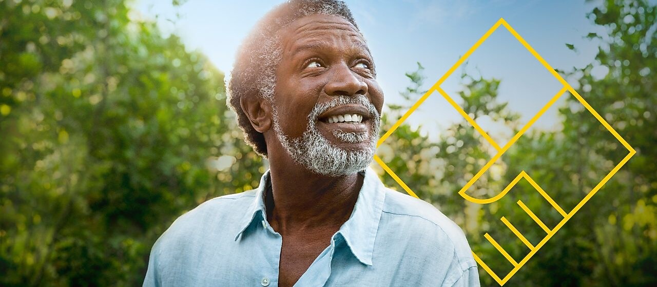 Hombre sonriente con barba frente a árboles con un gráfico de Generando valor para los accionistas