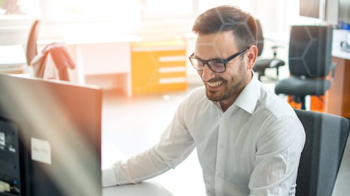 Hombre sonrie mirando a la pantalla de su computadora